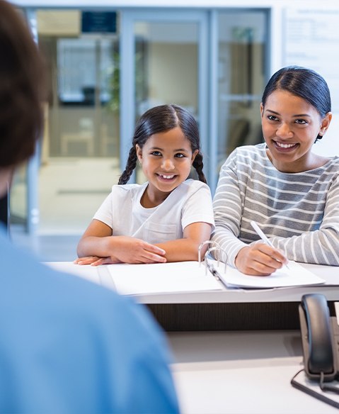 Mother and daughter discussing flexible payment options with dental team member