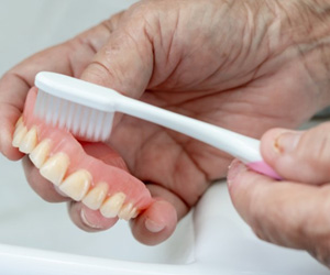 Patient brushing their denture