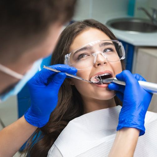 Patient opening wide as dentist cleans her teeth