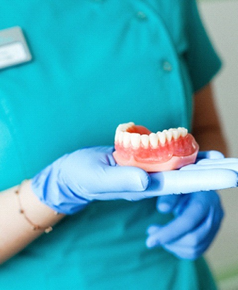 Closeup of Fayetteville dentist holding dentures in Fayetteville