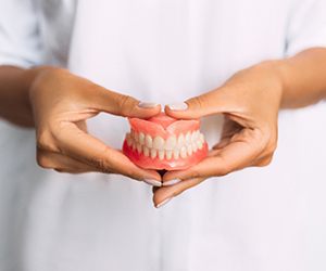 Dental patient holding up model of dentures in Fayetteville