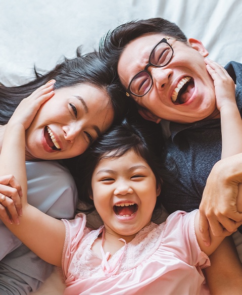 Mother father and daughter laughing after children's dentistry visit