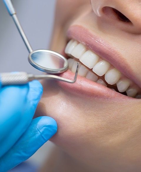 closeup of dental tools around the patient’s mouth  