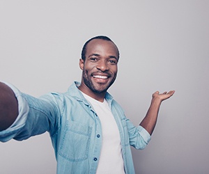 Man smiling while saving money because of dental implants in Fayetteville