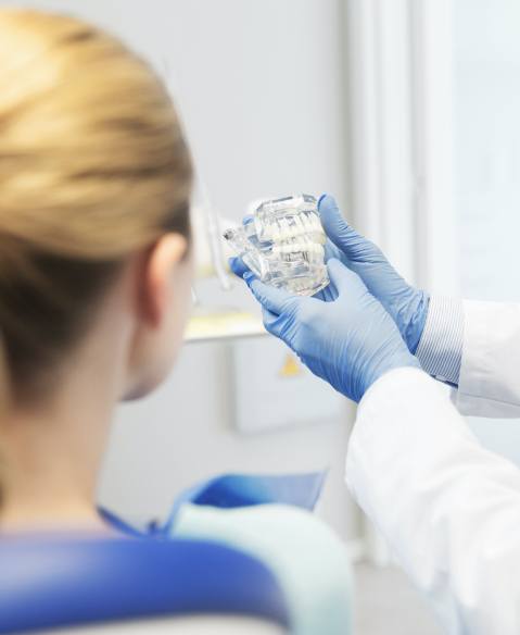 Dentist showing dentistry patient a model smile with a dental implant supported fixed bridge