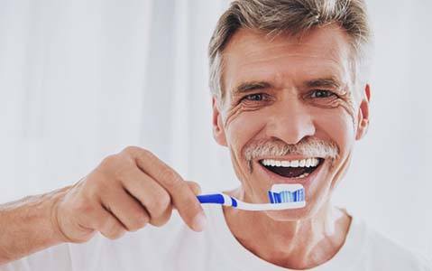 Man brushing his teeth because of the day-to-day benefits of dental implants in Fayetteville