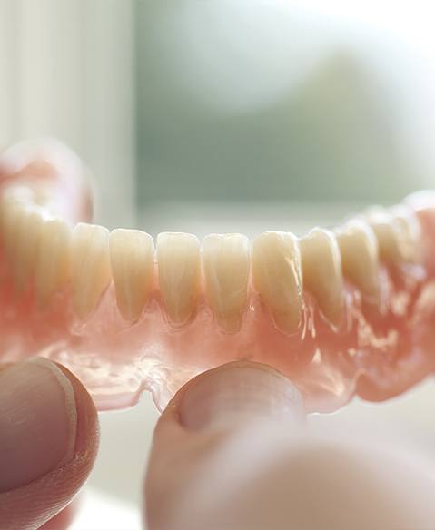 Hand holding a full denture