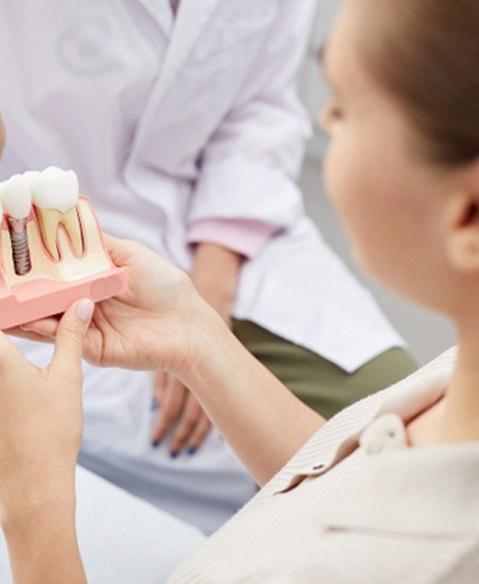 patient holding a model of a dental implant 