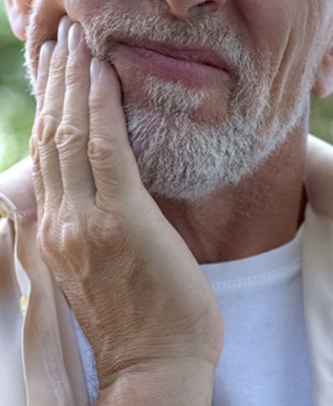 older man holding his face in discomfort 