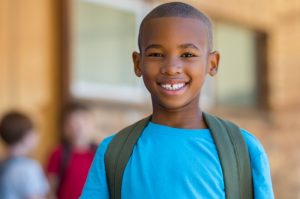 child with backpack going back to school and preventing dental emergencies