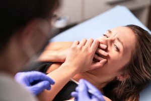 patient covering their mouth before a dental emergency procedure