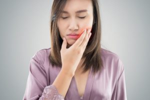 woman holding her face with facial swelling