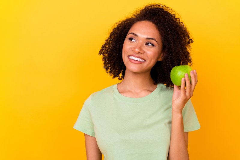 A woman with veneers holding an apple