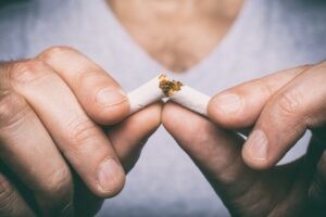 person breaking a cigarette showing that they’re quitting